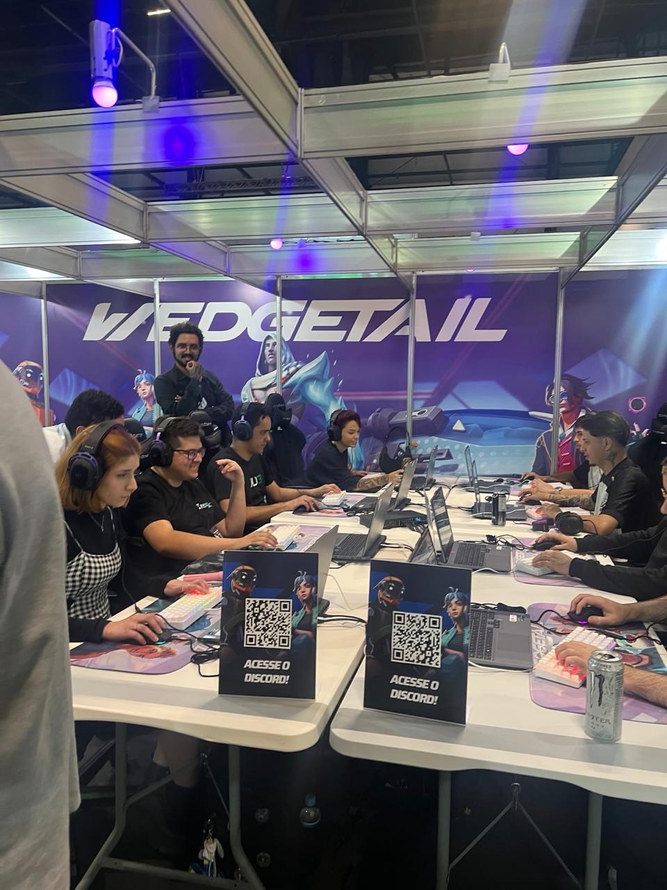 Jogadores lotando as mesas do estande do Wedgetail na BGS